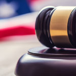 Judges wooden gavel with USA flag in the background. Symbol for jurisdiction.