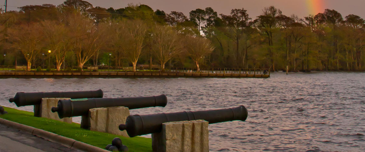 Cannons on the waterfront with a rainbow in the sky