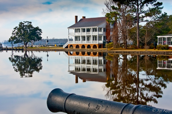 House on the waterfront with an old cannon across the way.